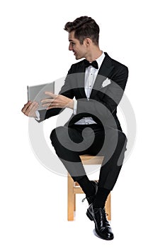 Happy young elegant man holding tab and presenting to side