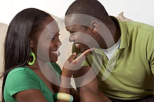 Happy young ethnic black couple sitting on couch