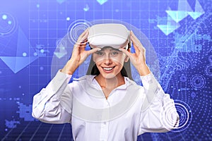 Happy young european businesswoman with VR glasses standing on creative glowing blue metaverse background. Cyberspace, augmented