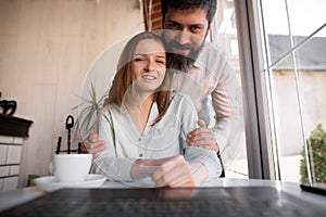 Happy young european couple resting at living room, waving hand hello using webcam laptop, greeting friends at online