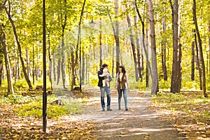 Happy young family in the autumn park outdoors on a sunny day. Mother, father and their little baby boy are walking in