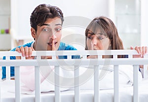 Happy young family at baby bed cot