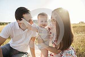 Happy young family with baby son playing and having fun together in nature on field