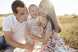 Happy young family with baby son playing and having fun together in nature on field