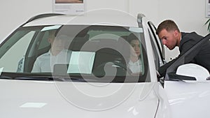 A happy young family buys a luxury car. Car sales manager showing a new car. Car sales concept