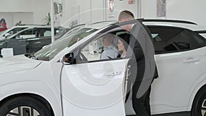 A happy young family buys a luxury car. Car sales manager showing a new car. Car sales concept