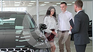 A happy young family buys a luxury car. Car sales manager showing a new car. Car sales concept
