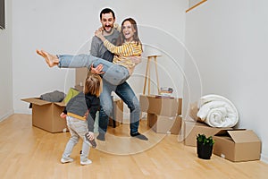 Happy young family celebrating moving to a new home, having fun together