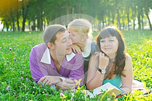 Happy young family with a child lying on the grass