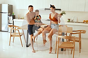 Happy young family with child in modern kitchen in summer