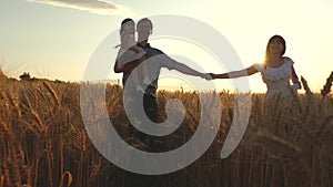 Happy young family with a child walks on a wheat field. father daughter and mother are playing on the field. Mommy Mom