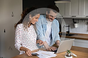 Happy young family couple calculating domestic expenditures.