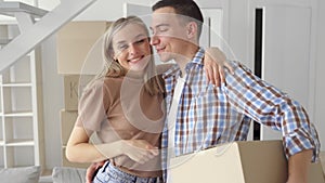 Happy young family couple embracing kissing at new home at moving day.