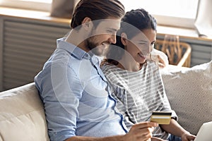 Happy young family couple involved in internet shopping at home.