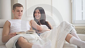 Happy young family couple sitting together on the couch and spending time at home