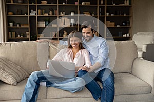 Happy young family couple using computer at home.
