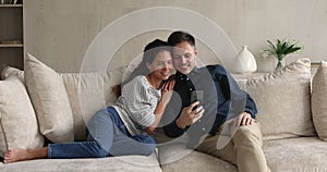 Happy young family couple using smartphone together at home.