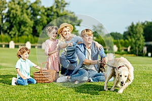 happy young family with dog resting on green grass