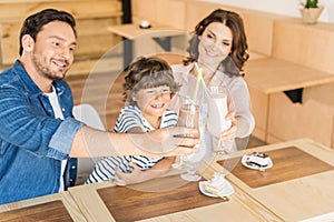 happy young family drinking milkshakes in cafe and spending