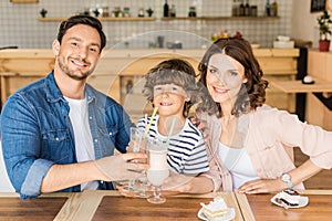 happy young family drinking milkshakes in cafe and spending