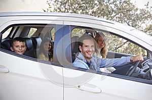 Happy young family driving in their car looking to camera