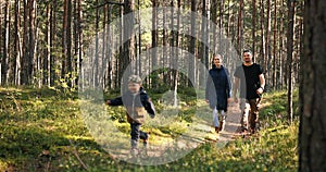 Happy young family enjoying walk in forest. running children