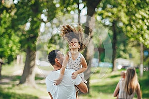 Happy young family father, mother and children having fun outdoors, playing together in summer park, countryside