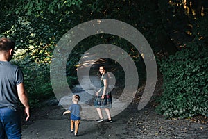 Happy young family father, mother and little son hugging and touching outdoors, playing together in summer park