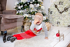 Happy young family, father, mother and son, in Christmas evening in home. A little boy is sitting on the floor near the tree with