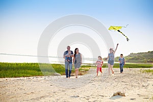 Happy young family with flying a kite on the beach
