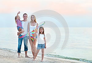 Happy young family with flying a kite on the beach