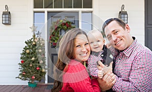 Happy Young Family On Front Porch of House With Christmas Decorations