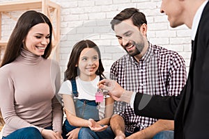 Happy young family gets keys to new house, which realtor helped to choose. Family buys house.
