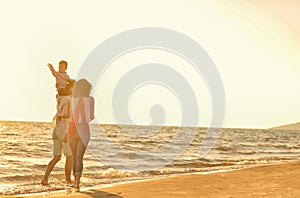 Happy young family have fun on beach run and jump at sunset