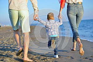 Happy young family have fun on beach run and jump at sunset