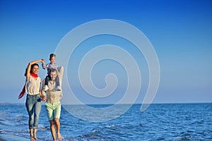 Happy young family have fun on beach run and jump at sunset