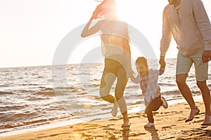 Happy young family have fun on beach run and jump at sunset