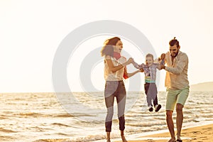 Happy young family have fun on beach run and jump at sunset