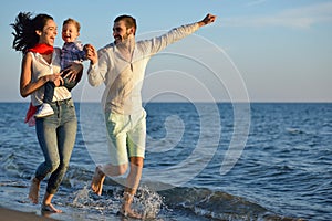 Happy young family have fun on beach run and jump at sunset