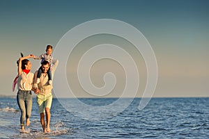 Happy young family have fun on beach run and jump at sunset