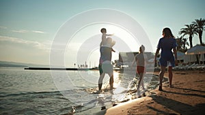 Happy young family have fun walking on beach at sunset. Family Silhouette Travel Holiday.