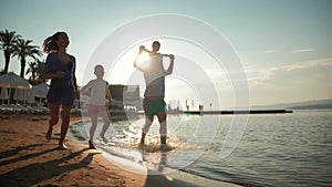 Happy young family have fun walking on beach at sunset. Family Silhouette Travel Holiday.