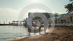 Happy young family have fun walking on beach at sunset. Family Silhouette Travel Holiday.