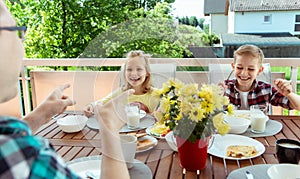 Happy young family having fun during breakfast on terrasse at home