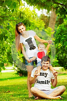 Happy young family is having fun in the green summer park outdoors on a sunny day. Mother, father and their little baby-boy are w
