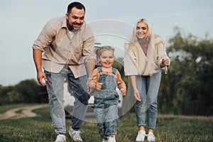 Happy Young Family Having Fun Outdoor, Little Daughter Playing Running Away from Her Parents