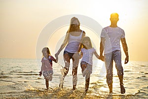 Happy young family having fun running on beach at sunset. Family