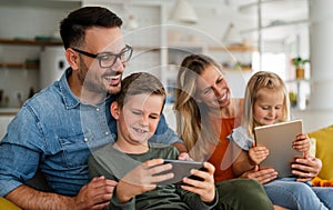 Happy young family having fun time at home. Parents with children using digital device.