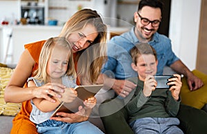 Happy young family having fun time at home. Parents with children using digital device.