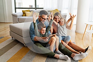 Happy young family having fun time at home. Parents with children using tablet